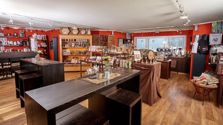 Ein einladendes Geschäft mit Holzregalen und einer Vielzahl von Produkten. Die Wände sind rot gestrichen und die Atmosphäre ist freundlich und warm.