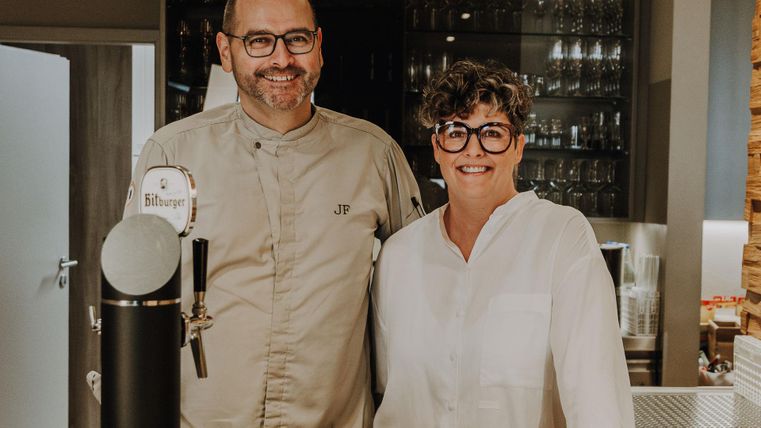 Jörg und Jessica Frankenbach stehen hinter der Bar. Sie lächeln und sind die Gastgeber vom Hotel Panorama.