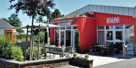 Een uitnodigend café met een kleurrijke uitstraling in een groene omgeving. Er zijn zitplaatsen in de buitenlucht en veel zonneschijn.