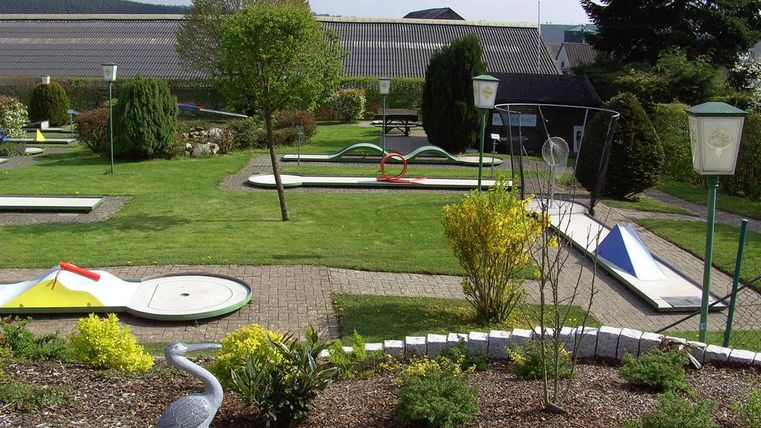 Een minigolfbaan met groen gras en verschillende speelbanen. Omringd door bomen en struiken, biedt de accommodatie een ontspannen sfeer.