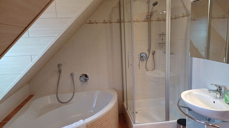 A modern bathroom with a bathtub and a separate shower. There is also a sink and generous windows for plenty of light.