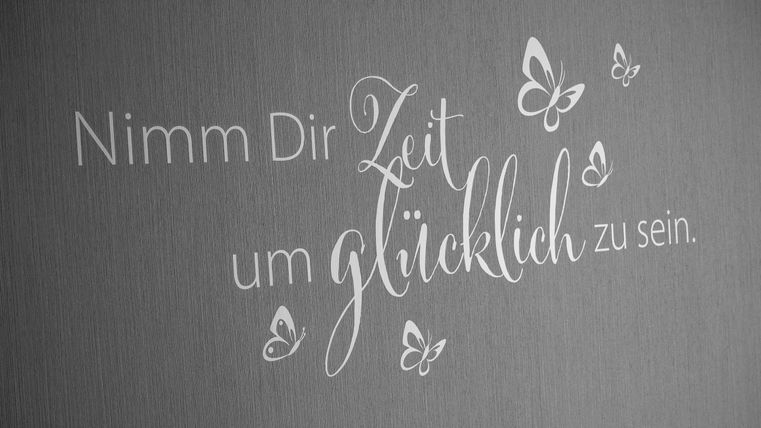 An inspiring quote on a wall. It encourages taking time to be happy.