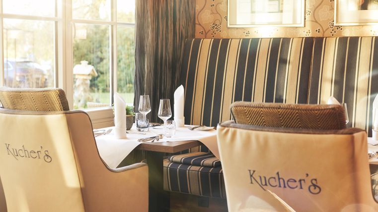 Ein elegantes Restaurant mit gestreiften Sitzbänken und Tischdecken. Es gibt dekorierte Tische und eine gemütliche Atmosphäre.