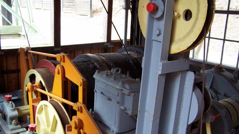 A machine with large gears and a variety of mechanical components. It looks like part of an old drive or elevator system.