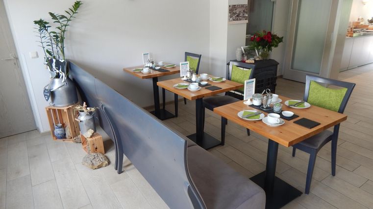 A modern restaurant with wooden-colored tables and stylish chairs. The atmosphere is friendly and inviting.