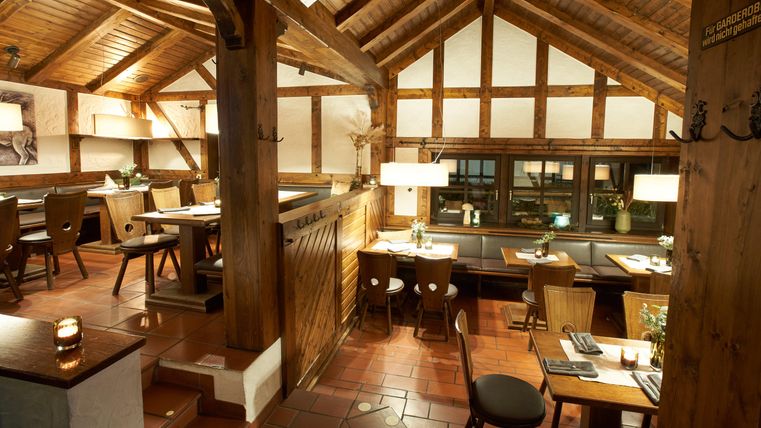 Ein gemütliches Restaurant mit einer Holzdecke und warmem Licht. Die Tische sind liebevoll eingedeckt und laden zum Verweilen ein.