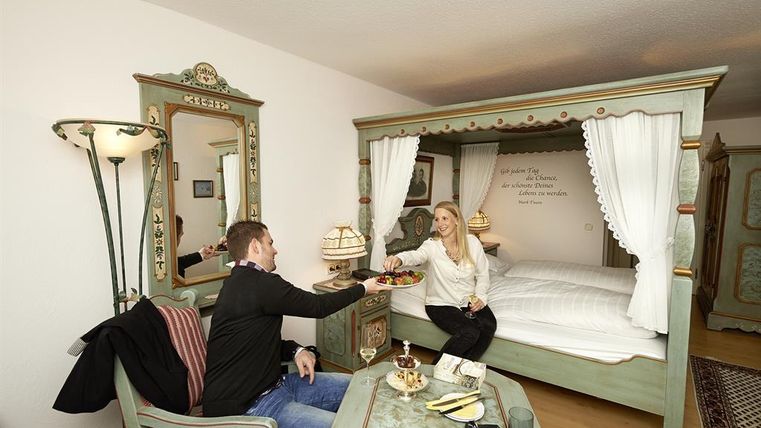 Ein gemütliches Zimmer mit traditioneller Einrichtung. Ein Paar sitzt zusammen und genießt Snacks.