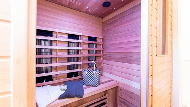 Eine moderne Sauna aus Holz mit einer entspannten Atmosphäre. Auf der Bank liegt ein Kissen und eine Tasche.