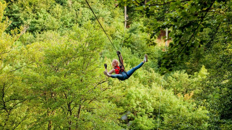 Woman hanging on a zipline in the forest
