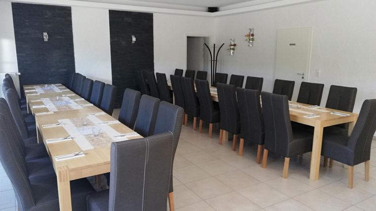 A bright, clean room with long tables and plenty of chairs. The room is ready for a meeting or event.