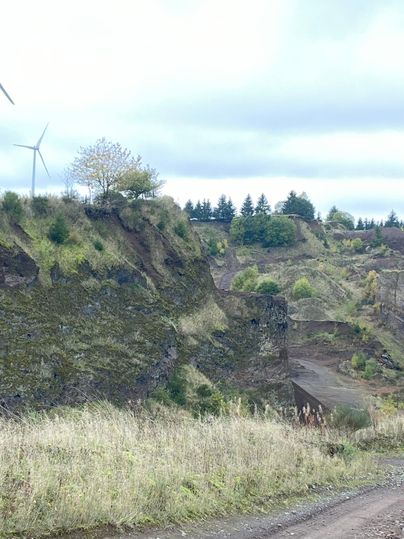 Hier hat man einen Ausblick auf den Vulkan. Man sicht leicht bewachsene Hügel. Der Himmel ist bewölkt.