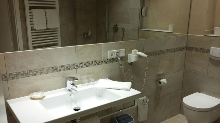 A modern bathroom with bright tiles and a sink. Towels and toiletries are neatly arranged.