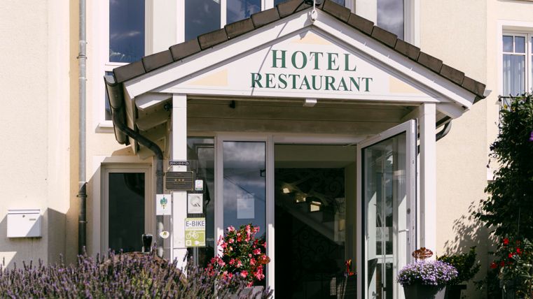 Ein einladendes Hotel mit einem Restaurant. Der Eingang ist blumenreich geschmückt.