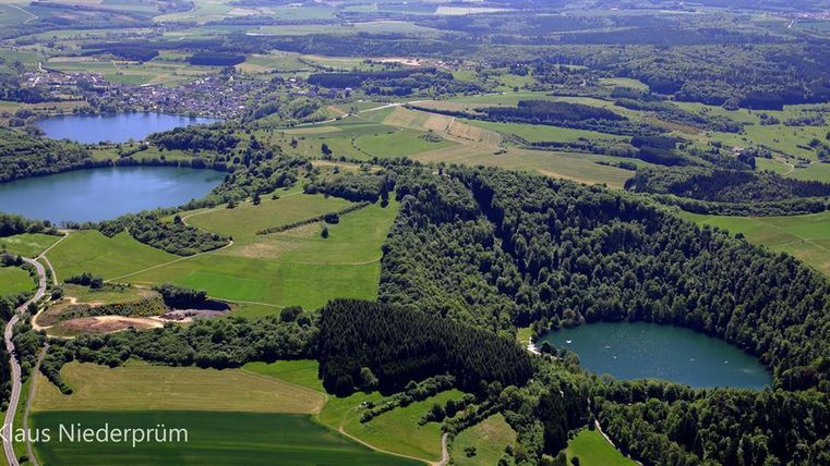 Een schilderachtig landschap met meerdere meren en weelderige groene bossen. Het gebied is omgeven door zachte heuvels en biedt een rustige, natuurlijke sfeer.