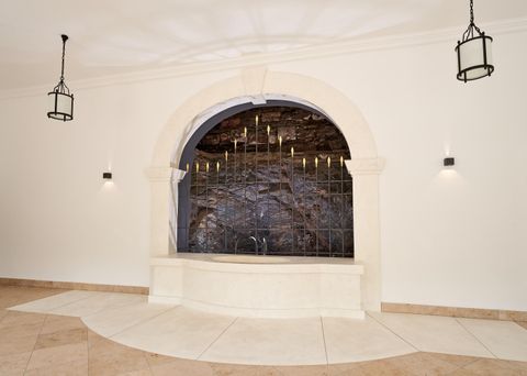 An elegant wall with a water basin and a decorative stone wall. Soft lighting and architectural details create a tranquil atmosphere.