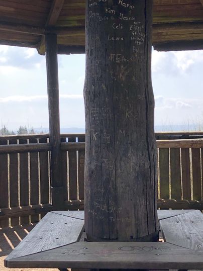 Ein rustikaler Aussichtsturm mit einem Holzsäule in der Mitte. Der Platz bietet einen Blick auf die Landschaft.