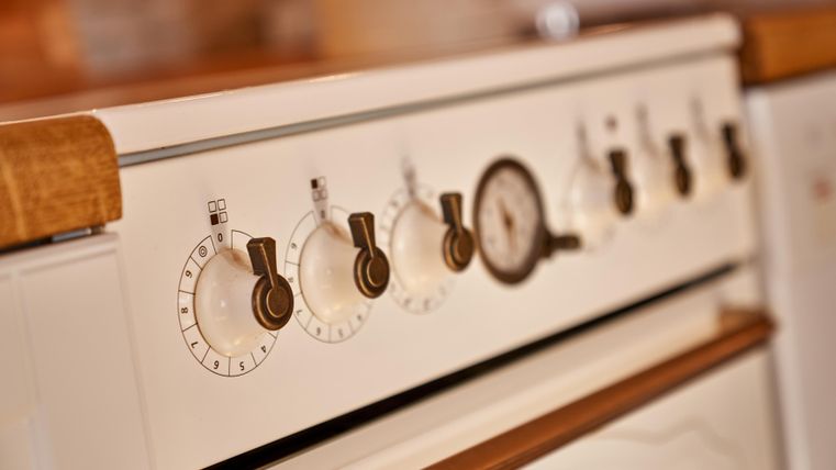 A classic stove with knobs and a pressure gauge. The combination of wood and white gives it an elegant appearance.