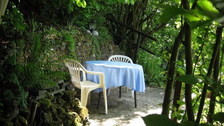 Een gezellige tafel met een blauwe tafelkleed staat in het groen. Omringd door planten en bomen nodigt de hoek uit om te ontspannen.