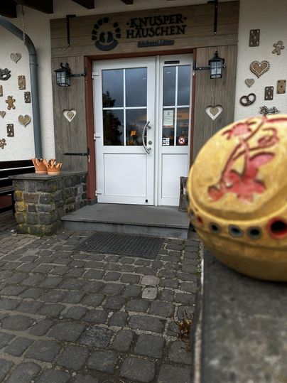 Een uitnodigende winkel met een heldere ingang deur en decoratieve elementen aan de muur. Op de voorgrond staat een kleurrijk keramiekobject.