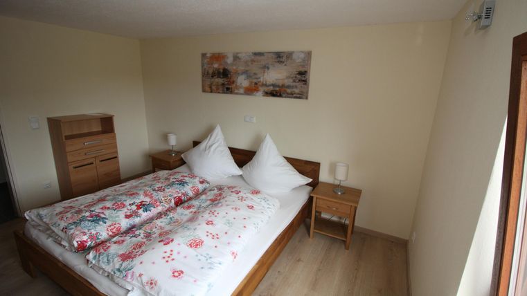 Een comfortabele slaapkamer met een groot bed en kleurrijke kussens. Naast het bed staan nachtkastjes en er is een harmonieuze wanddecoratie.