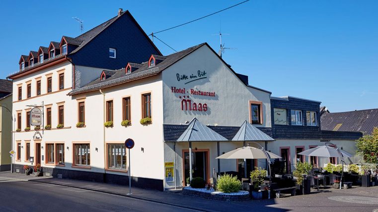 Een charmant hotel met een restaurant aan de straatzijde. Het heeft een lichte gevel en een uitnodigend terras.