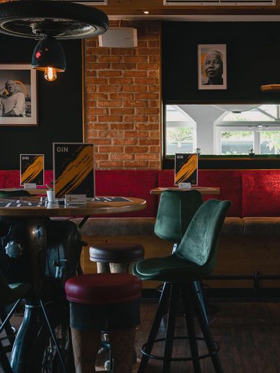 Eine gemütliche Bar mit Holzstühlen und einem rustikalen Ambiente. An den Wänden hängen dekorative Bilder und es gibt Menüs auf den Tischen.