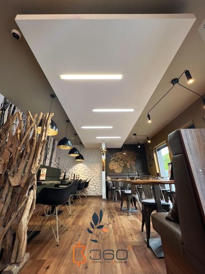 Een modern restaurant met houten elementen en stijlvolle lampen. De vloer is van hout en de muren zijn smaakvol gedecoreerd.