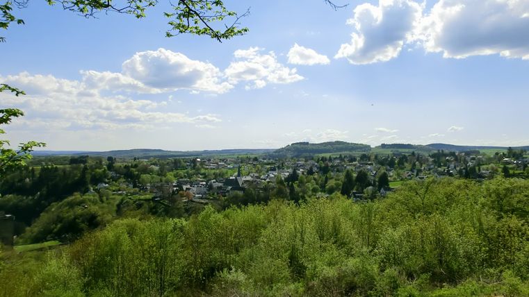 Aussicht auf Manderscheid mit grüner Landschaft und blauem Himmel.