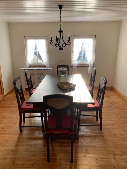An inviting dining area with a large table and stylish chairs. The windows let in plenty of daylight, creating a bright, friendly atmosphere.