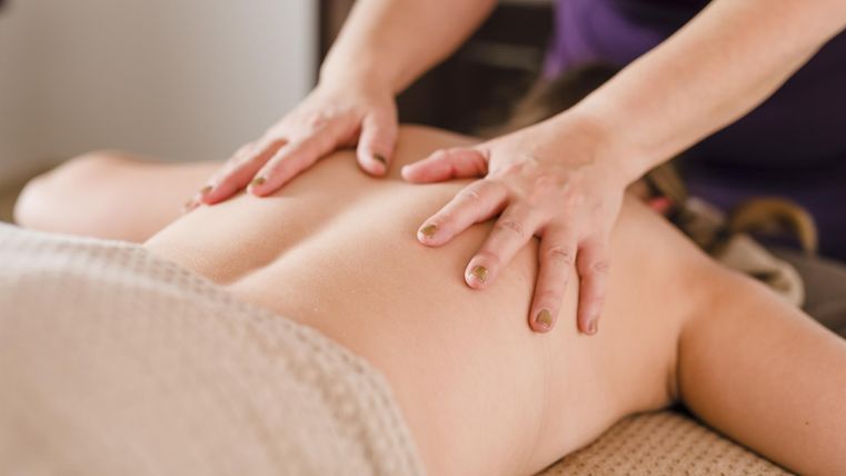 Eine Person erhält eine entspannende Massage auf einer Liege. Die Hände des Masseurs arbeiten sanft am Rücken.