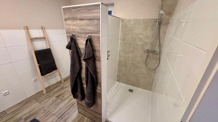 Ein großzügiges und modernes Tageslicht- Bad mit begehbarer Dusche, einem großen Waschbecken, einer Toilette und Ablagemöglichkeiten.