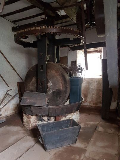 Eine alte Maschine in einem rustikalen Raum. Der Boden ist aus Holz, und es gibt einige Werkzeuge in der Umgebung.