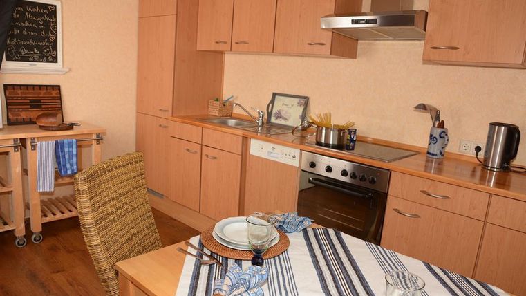 A modern kitchen with wooden cabinets and appliances. The table is set with dishes and cutlery.