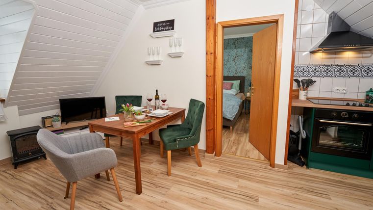 A cozy apartment with a dining area and a modern kitchen. The furnishings are bright and inviting, perfect for relaxing.