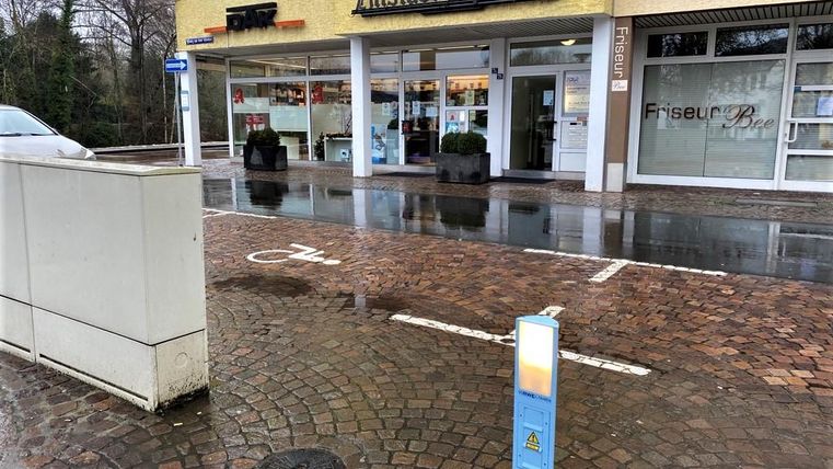 A pharmacy named "Altstadt-Apotheke" is located at a street corner. The ground is wet, probably from rain, and parked cars can be seen.