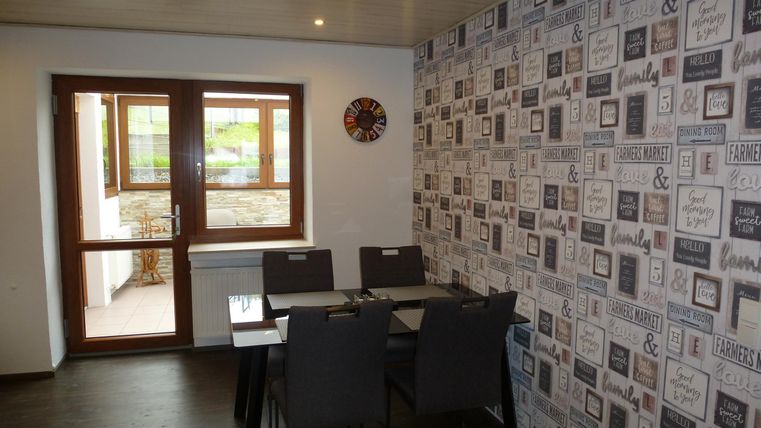 Ein moderner Essbereich mit einem Tisch und Stühlen. Die Wand ist mit einem kreativen Muster dekoriert und ein Fenster sorgt für Tageslicht.