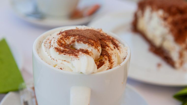 Cup of cocoa and in the background a piece of cake