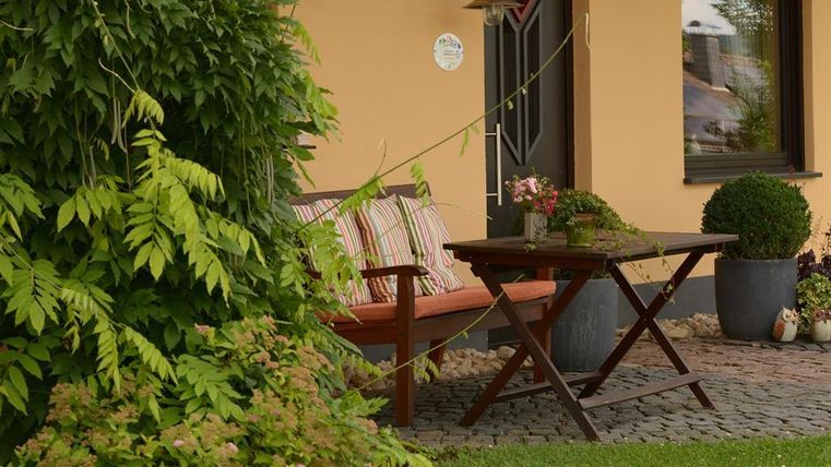 A cozy outdoor area with a bench and a table.
Surrounded by green plants and a welcoming atmosphere.