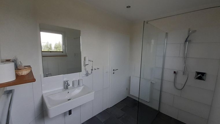 Ein modernes Badezimmer mit einer Dusche aus Glas und einem eleganten Waschtisch. Helle Wände und Fliesen schaffen eine einladende Atmosphäre.