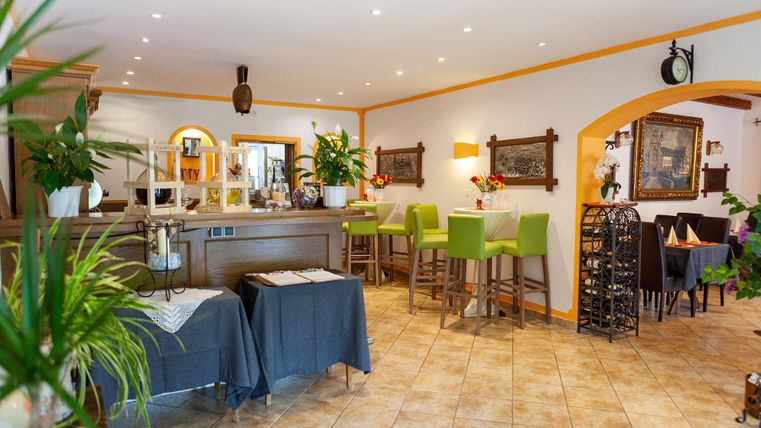 Innenansicht eines gemütlichen Restaurants mit grünen Stühlen und Holztischen.