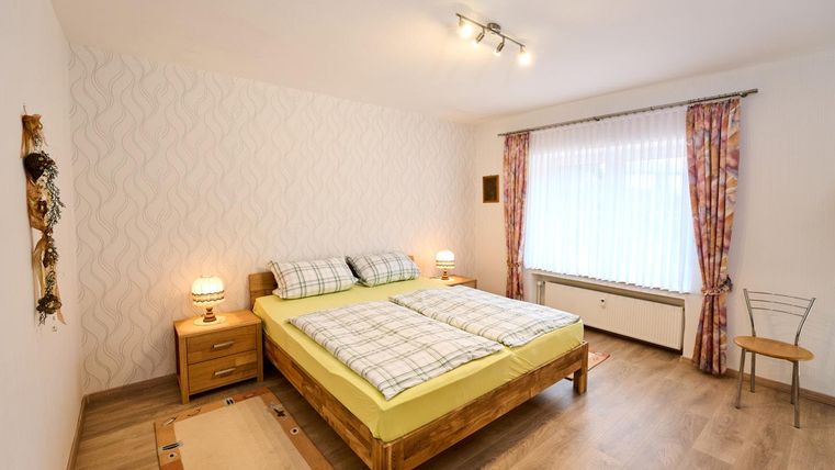 Ein gemütliches Schlafzimmer mit einem Doppelbett und einem großen Fenster. Die Wände sind hell und die Dekoration ist schlicht und modern.