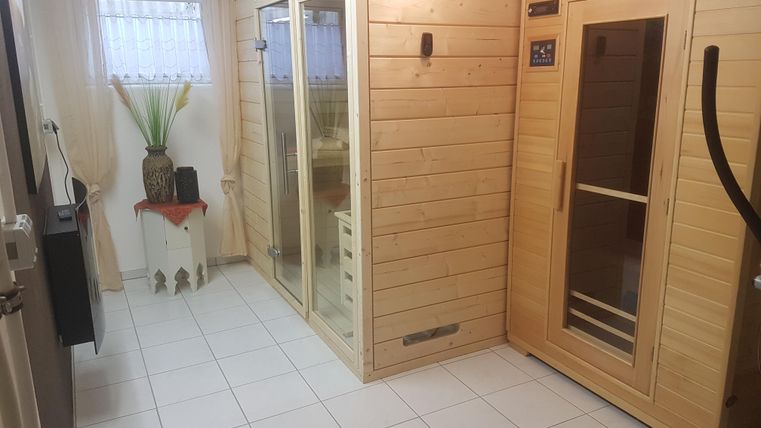 Ein gemütlicher Wellnessbereich mit zwei Saunen und einem großen Fenster. Die Wände sind aus Holz und der Boden ist gefliest.