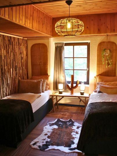 A cozy bedroom with two single beds. Soft lighting and natural materials create an inviting atmosphere.