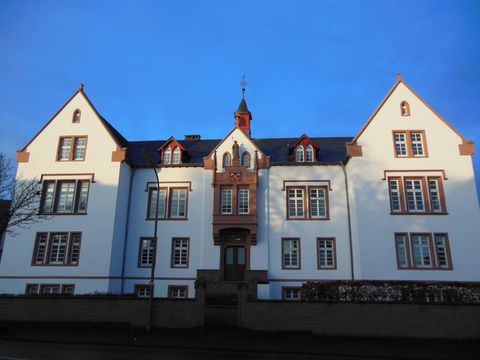 A historical building with a white facade and red accents. The sky is clear and blue.