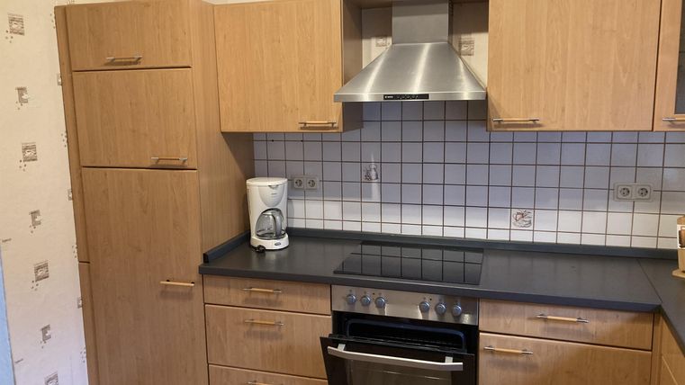 Een moderne keuken met houtlook en zwarte werkbladen. De ruimte is helder en vriendelijk ingericht.