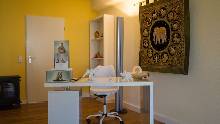 Ein modernes Büro mit gelben Wänden und einem eleganten Schreibtisch. Dekorative Elemente und ein Wandteppich verleihen dem Raum eine einladende Atmosphäre.