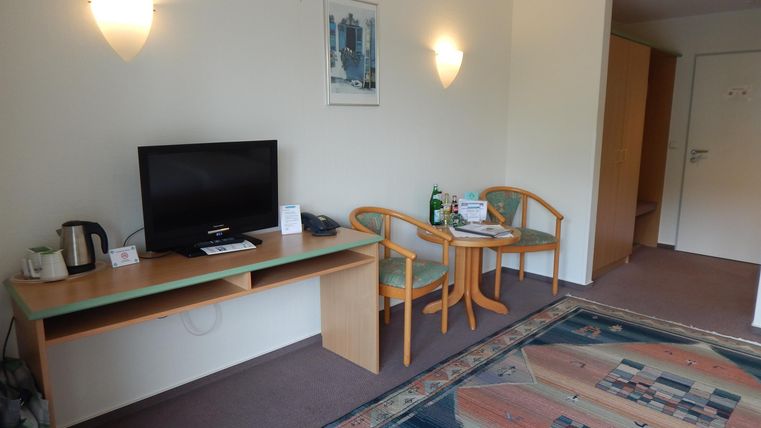 A simple hotel room with a television, a table, and two chairs. The room is bright and cheerfully designed.