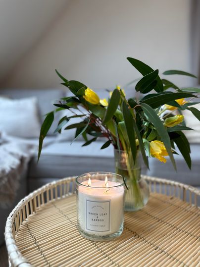 Een gezellige tafelversiering met een kaars en een bloemenboeket. De bloemen zijn geel en groen, terwijl de kaars zachtjes straalt.