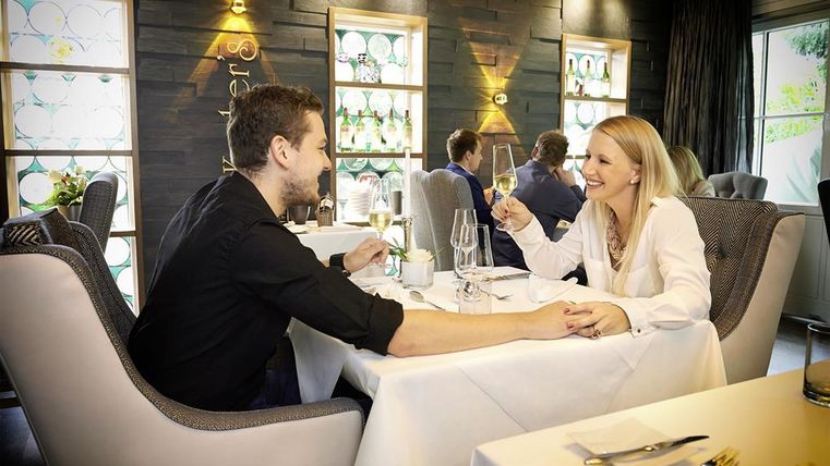 Ein romantisches Abendessen in einem eleganten Restaurant. Ein Paar lächelt sich an und genießt gemeinsame Gespräche bei Kerzenlicht.