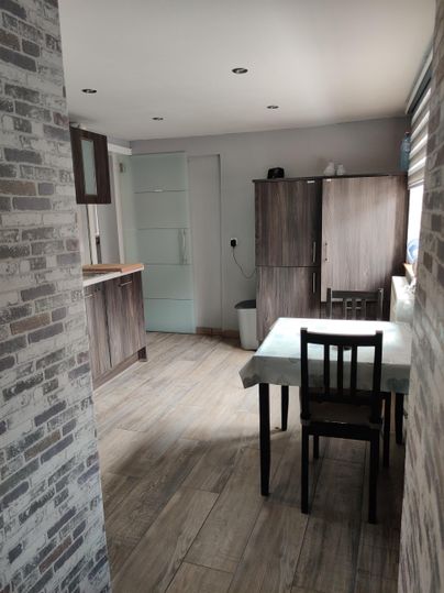 A modern kitchen with a dining area. The room is bright and welcoming, with wooden flooring and contemporary furnishings.